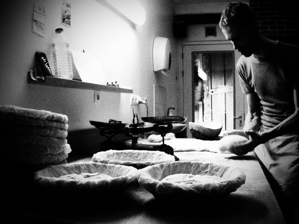photo noir & blanc d'un boulanger en train de bouler un pâton afin de le mettre dans un banneton.