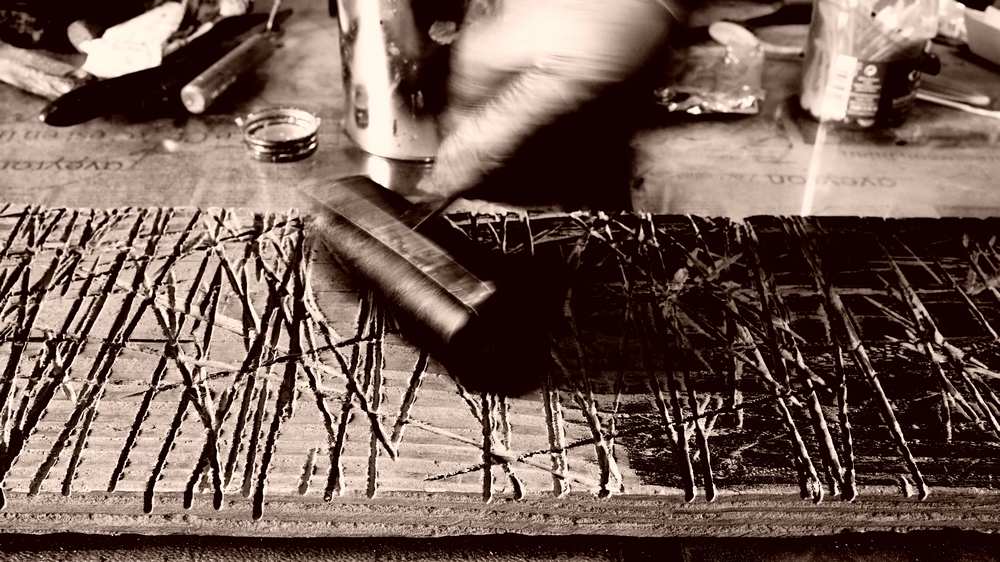 rouleau encreur en train d'encrer une planche de bois